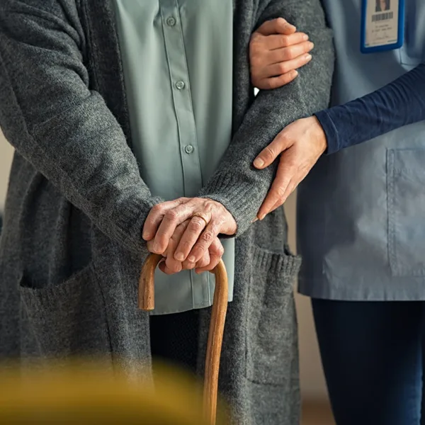 Nurse assisting an older adult walking with cane