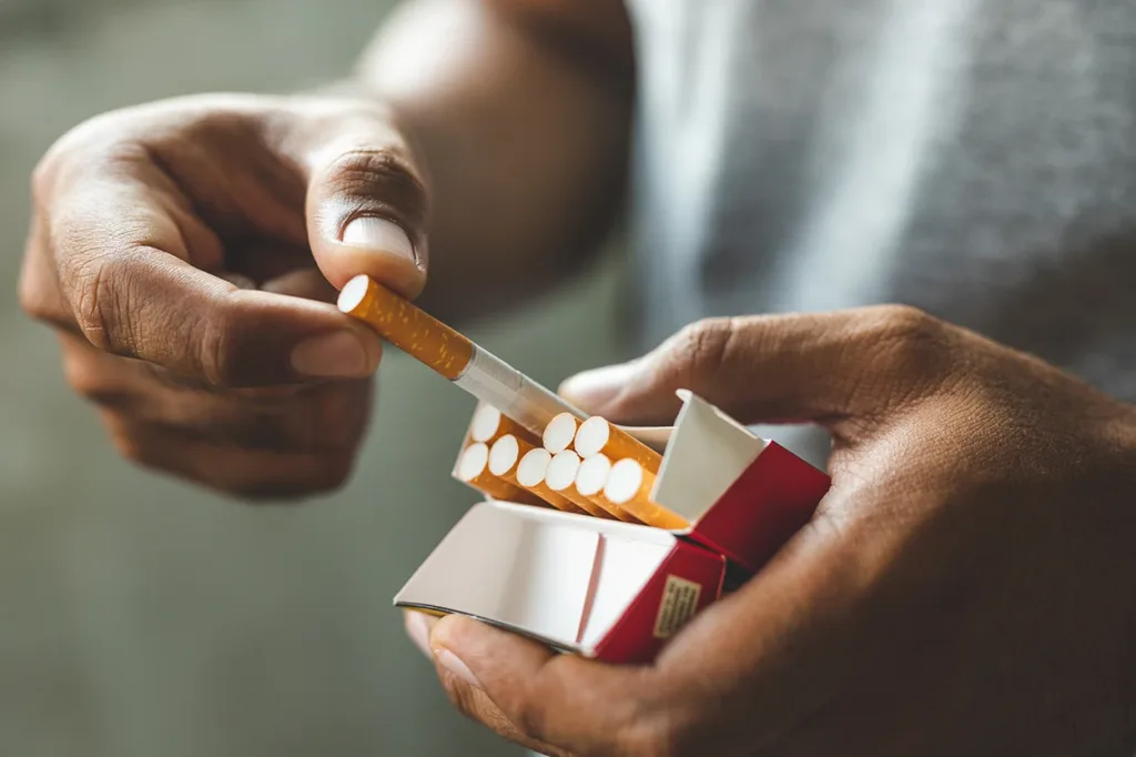 Close up male hand taking a cigarette out of a pack.