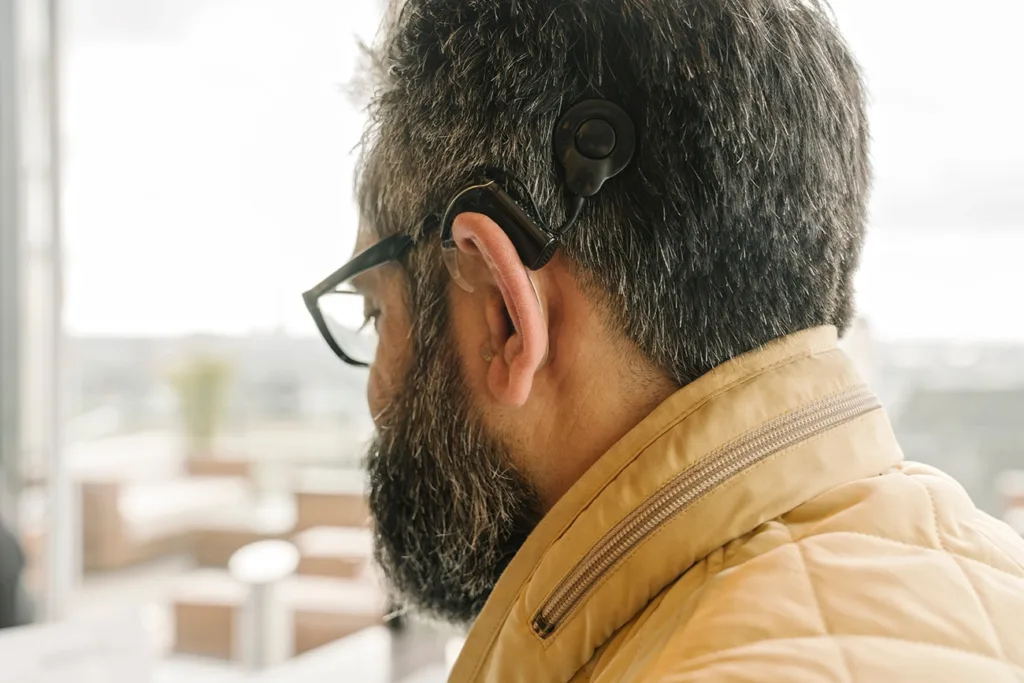 The side profile of a middle aged man with a conduction hearing aid