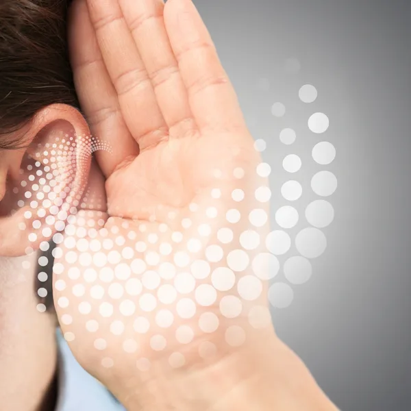 The side profile of an adult, holding the hand up to their ear trying to hearing more clearly, indicating that they may have hearing loss and need a hearing aid