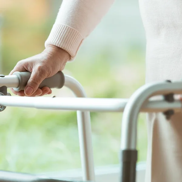A close up on the handles of a walker, mobility aid, being used by a senior women to help with balance issues associated with hearing loss