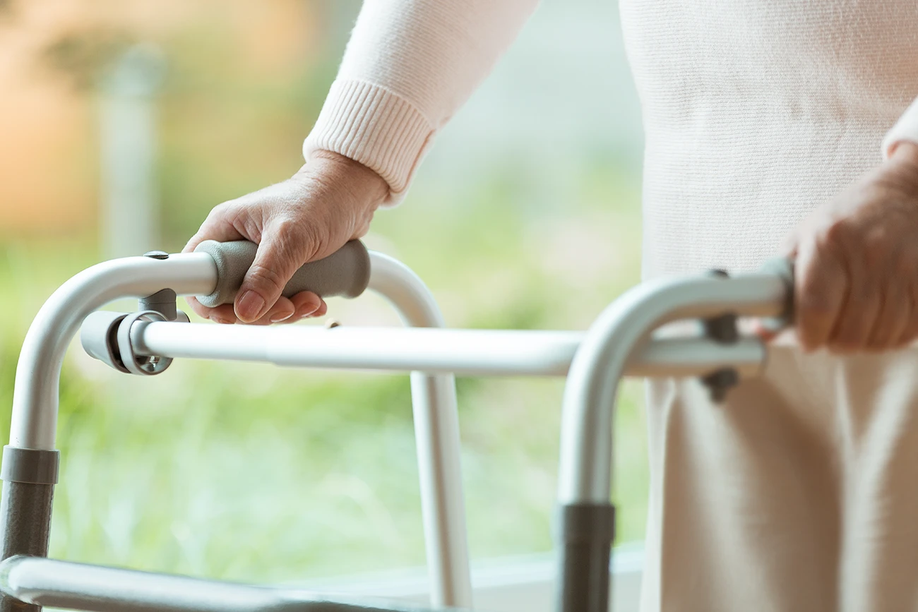 A close up on the handles of a walker, mobility aid, being used by a senior women to help with balance issues associated with hearing loss