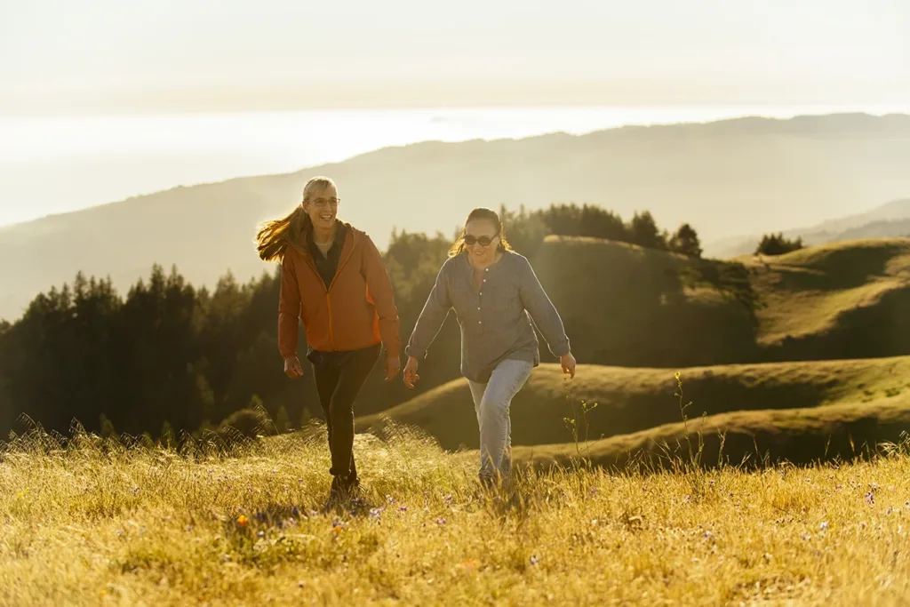 Two older adult women, happily hiking Mount Tamalpais, known locally as Mount Tam, in Marin County, California, just north of San Francisco, symbolizing how hearing aids can support physical health. 
